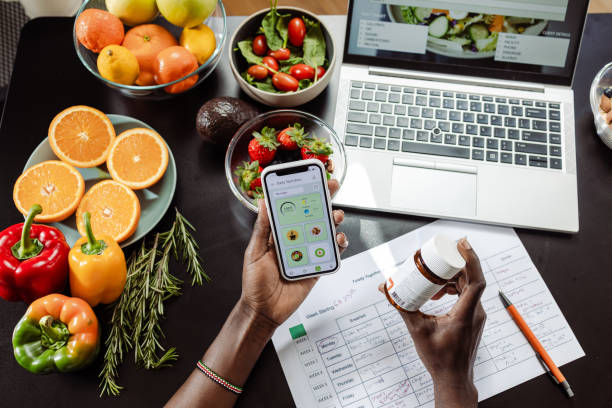 Alimentos y suplementos junto a una computadora y celular. La Cosmopolitana incursiona en estos nuevos enfoques.